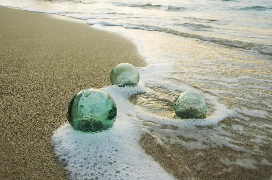 Three Glass Fishing Floats Roll On The Sandy Shoreline With Ripples Of  Water And Seafoam - PacificStock